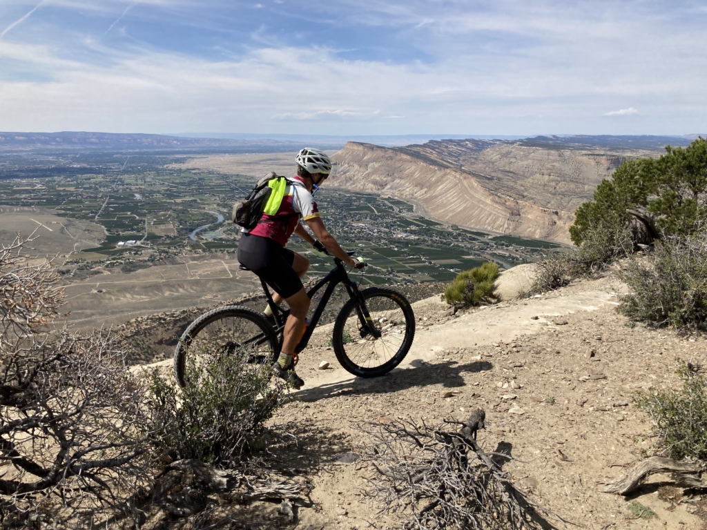 A mountain biker crosses a cliff along the Palisade Plunge trail in Colorado.